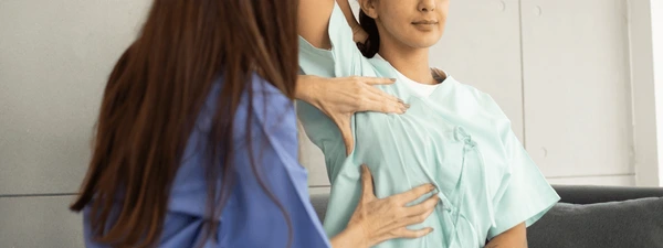 Two healthcare professionals assist a pregnant patient, hands placed on the baby bump during a prenatal check.